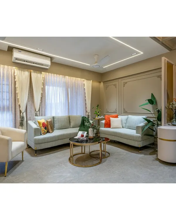 A full view of a modern living room designed for comfort and style. The neutral color palette is accented with pops of color from the cushions, while the elegant curtains and wall mouldings add a layer of sophistication.