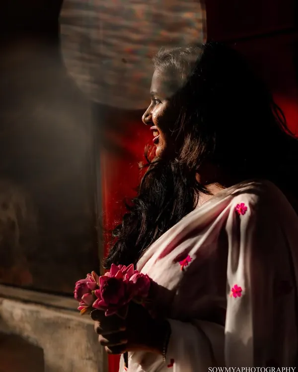 A bride-to-be holds a bouquet of lotuses, her smile illuminated by a ray of sunlight. This shot is from a pre-wedding series we did on the old streets of Bengaluru.