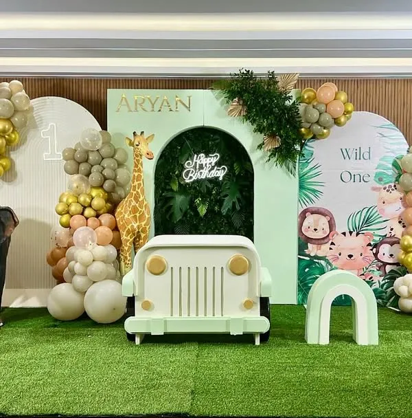 Get ready for a jungle adventure with Aryan's 'Wild One' first birthday party. We created a full safari scene with a jeep prop, life-sized giraffe and zebra figures, and lush greenery, all set against a custom backdrop with cute jungle animals.
