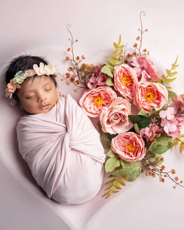 A little flower child, nestled in a heart and surrounded by pink blossoms. We use props like this heart-shaped bowl to create artistic and beautiful newborn portraits.