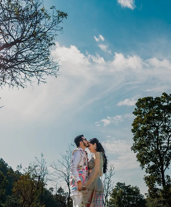 A kiss under the vast blue sky, surrounded by the mountains. This wide-angle shot captures the epic scale of nature, making their intimate moment feel even more special.