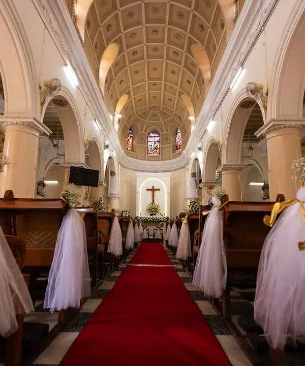 The aisle is ready. A wide shot of the beautifully decorated church, capturing the serene and grand atmosphere before the ceremony begins.