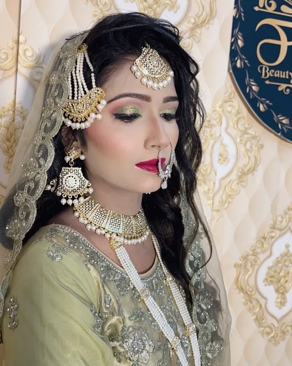 A complete Muslim bridal look featuring soft green and gold cut-crease eyeshadow, bold red lips, and perfectly placed traditional jewelry. I teach my students how to create these flawless, long-lasting bridal transformations.