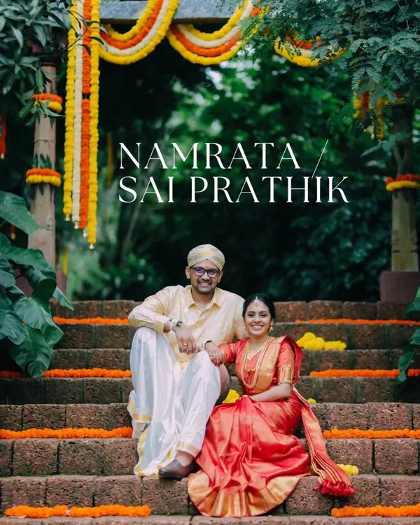 A classic portrait of Namrata and Sai Prathik at The Peacock Grove, surrounded by traditional marigold decor. This shot captures the timeless elegance of a South Indian wedding.