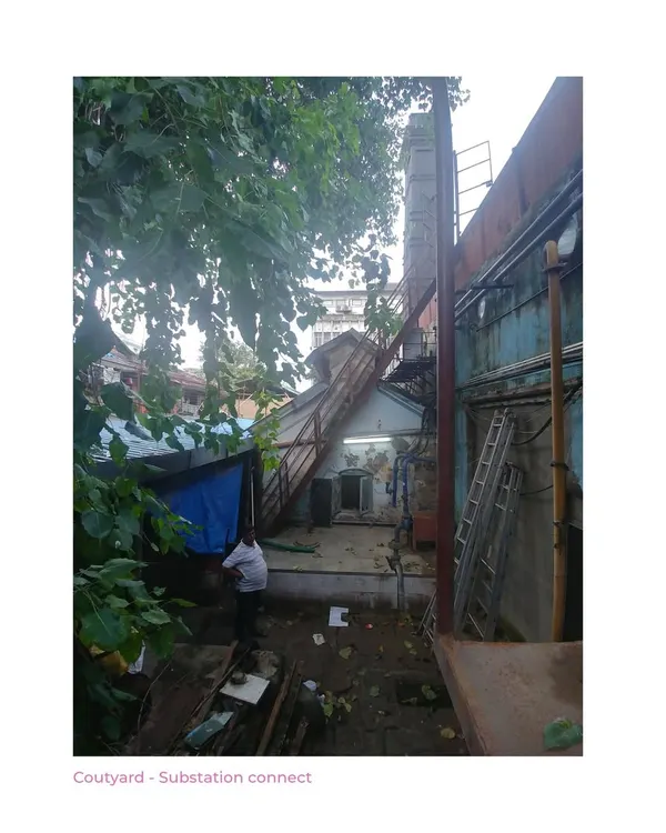 The courtyard of the Ambico Ice Factory before our intervention. This image documents the cluttered state, with ad-hoc structures choking the banyan tree and obscuring the building's original connection to the street.