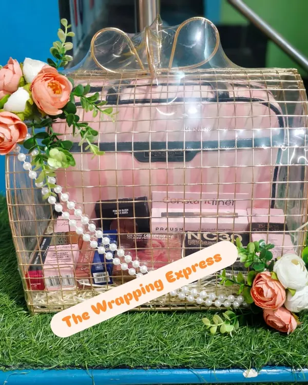 A very stylish makeup hamper packed in a golden wire basket. It's filled with products from brands like MAC and decorated with peach and white flowers.