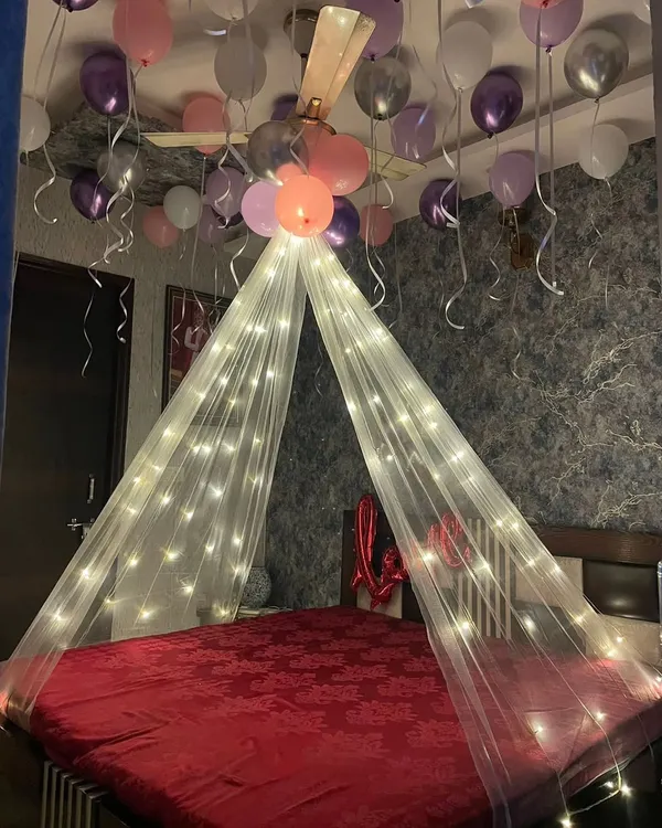 A simple and romantic bedroom canopy decoration. We used a sheer white canopy with fairy lights and surrounded it with pink, purple, and white balloons on the ceiling.