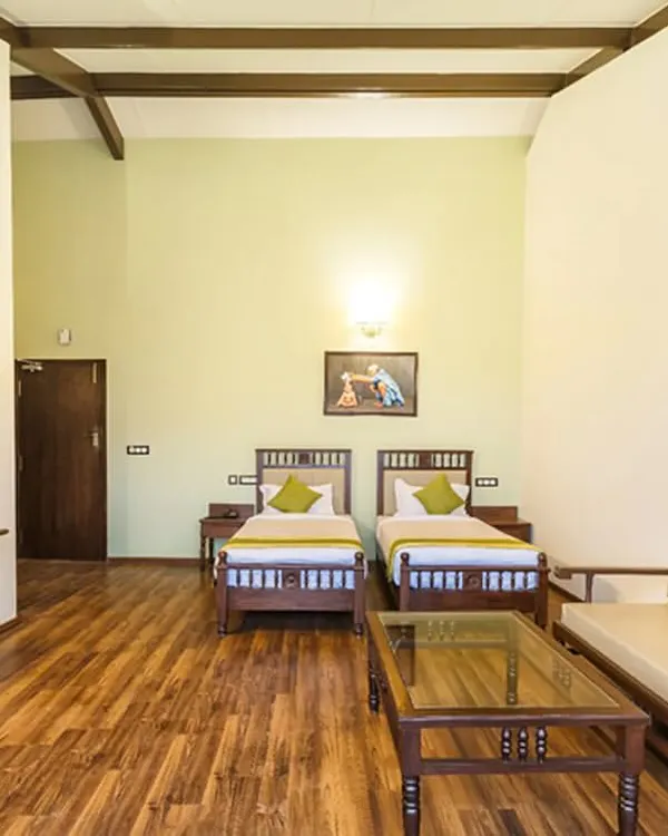 This is one of our spacious twin rooms, featuring comfortable beds, a seating area, and elegant wooden furniture. The room is designed to be a peaceful and clutter-free space for relaxation.
