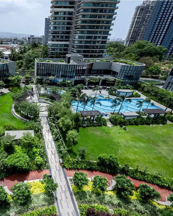 An aerial view of a lush residential development, showcasing the integration of a large central lawn, swimming pool, and extensive green roofs. Our designs transform high-density projects into green, livable communities where residents can connect with nature.