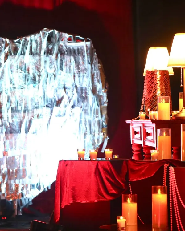 A cozy and dramatic corner from the 'Scarlet Splendor' event, featuring a crushed silver foil backdrop, red velvet, and an abundance of candles.