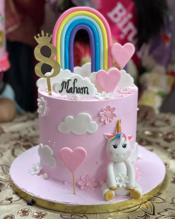 A magical unicorn and rainbow cake for an 8th birthday. This cake features a cute, hand-sculpted fondant unicorn, fluffy clouds, and a colorful rainbow topper.
