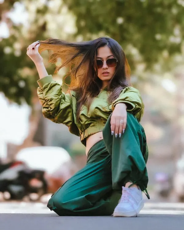 A dynamic low-angle shot from a street style session. The model's pose is strong and confident, and the movement in her hair adds a sense of action and spontaneity.