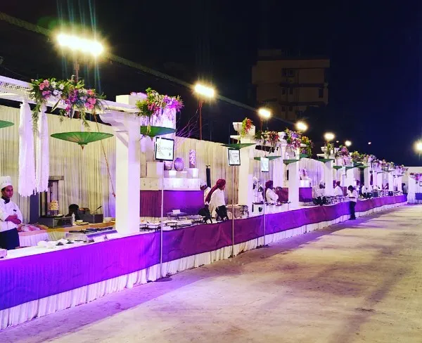 A grand buffet line under the stars, featuring elegant white counters with vibrant purple skirting. This setup is designed for large-scale weddings, ensuring a smooth flow for guests while adding a touch of color and sophistication to the evening.