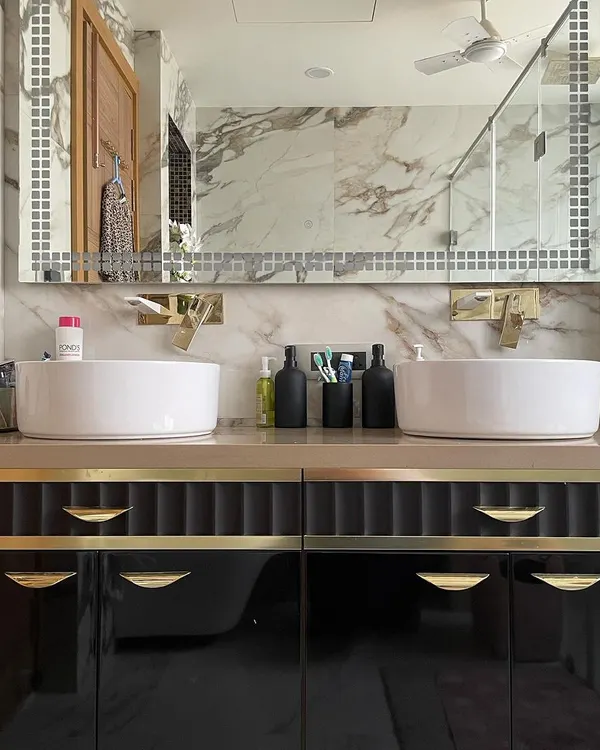 A bathroom should be a personal sanctuary. In this design, we contrasted the beautiful natural veins of Calacatta marble with a bold, black double vanity. The custom unit features fluted details and brushed gold hardware for a touch of timeless glamour.