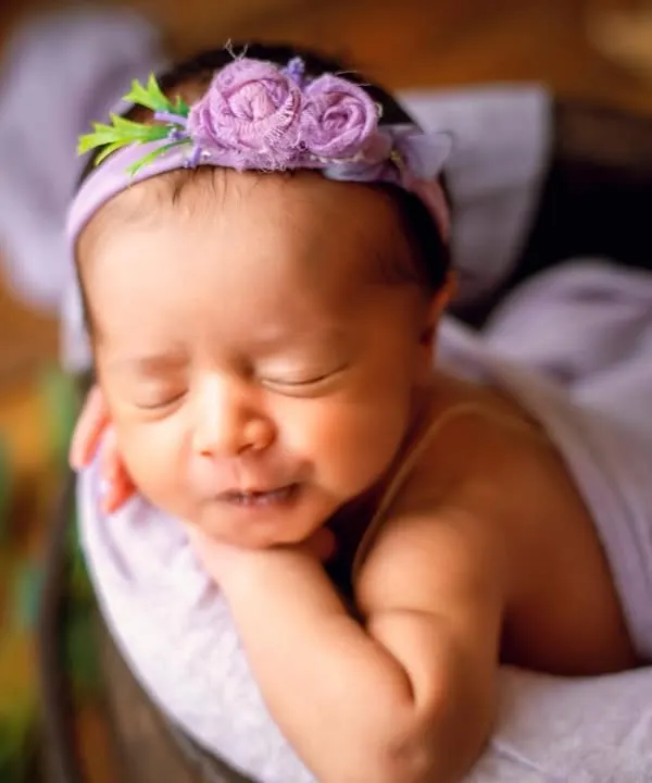 A sweet smile from a sleeping baby, nestled in a bucket with a lavender wrap and floral headband. I love coordinating colors to create a harmonious and artistic portrait.