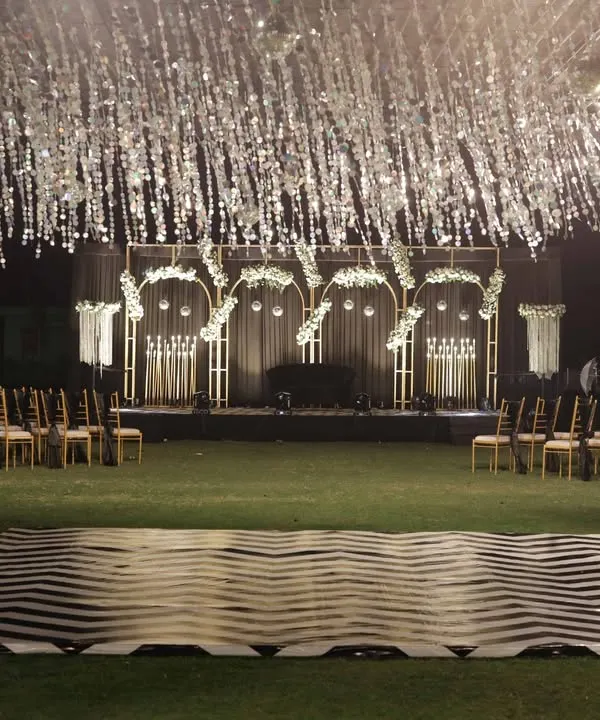 A stunning sangeet night setup featuring a custom chevron-patterned dance floor and a shimmering tinsel canopy, ready for an evening of performances.