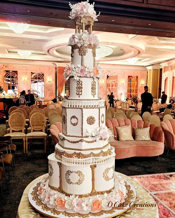This is the kind of edible masterpiece we love to create. A magnificent, multi-tiered architectural cake designed to be the absolute centerpiece of a grand wedding reception, featuring intricate gold detailing and delicate sugar flowers.