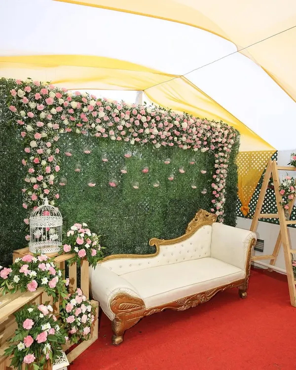 A beautiful setup for an intimate lockdown wedding. We created this photo corner with a floral green wall and elegant seating under a tent, proving that a small space can still be grand.