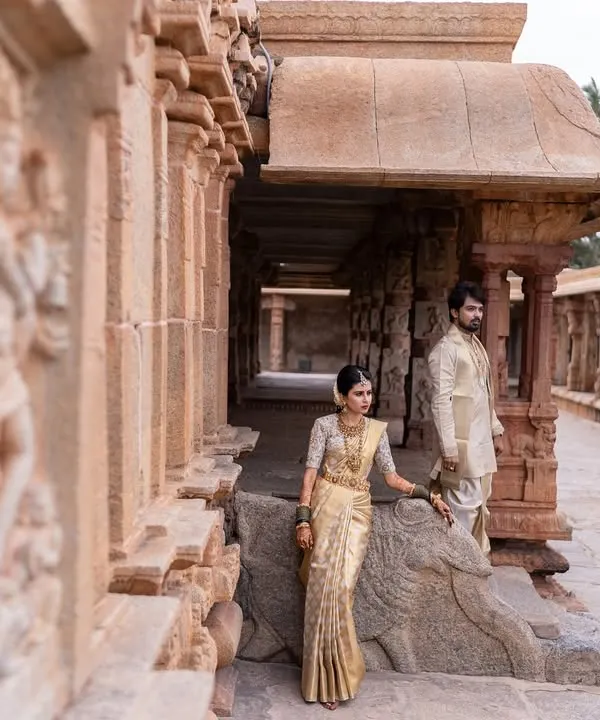 A majestic portrait of a couple in traditional South Indian attire at a heritage temple site, blending their love story with timeless culture.