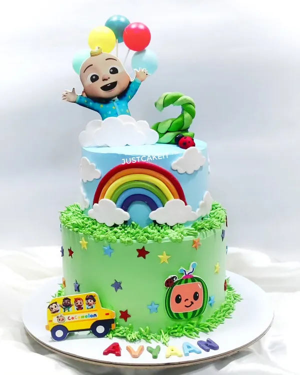 This two-tiered Cocomelon cake is full of cheerful details, including a rainbow, balloons, and the iconic school bus. The chocolate truffle cake inside was a big hit at the second birthday party.