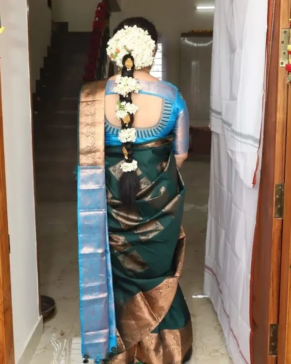 A classic South Indian bridal braid adorned with fresh jasmine flowers. This timeless hairstyle, paired with a beautiful blouse cutout, is a hallmark of a traditional muhurtham look.