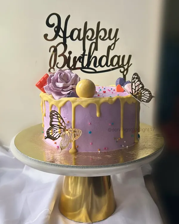 A lovely lavender birthday cake with a yellow drip, buttercream roses, and delicate butterfly accents. This design is both playful and elegant.