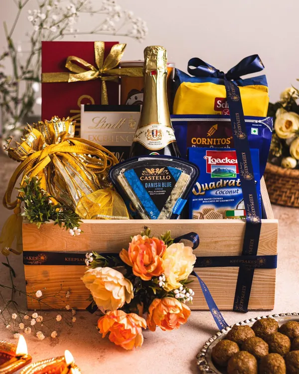 A luxurious gourmet hamper perfect for celebrations, featuring sparkling wine, Castello cheese, and premium snacks. Presented in a signature wooden crate with floral details, this is an ideal gift for Diwali or as a high-end wedding favour.