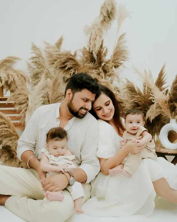 A quiet, tender moment with a family and their newborn twins. The neutral tones and soft textures of the boho setup create a serene atmosphere for this beautiful family portrait.