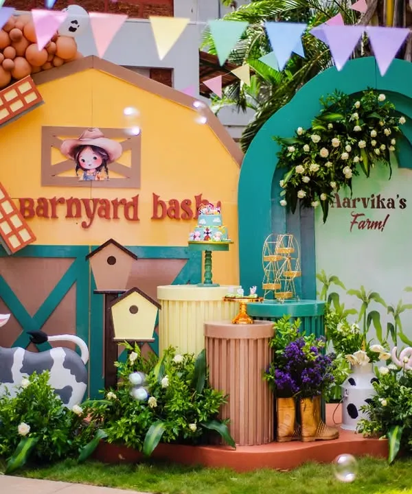 Welcome to Aarvika's Barnyard Bash! This full stage setup features a colorful barn, a windmill, and adorable cow and pig props, all surrounded by bubble machines for extra fun.