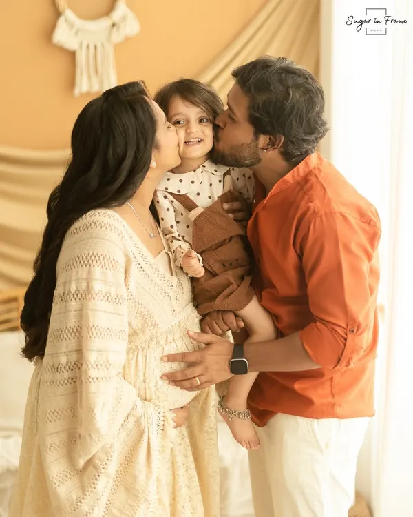 A beautiful family moment filled with love and anticipation. We captured mom and dad kissing their daughter's cheek as they celebrate the upcoming arrival of their new baby in our cozy, boho-themed studio.