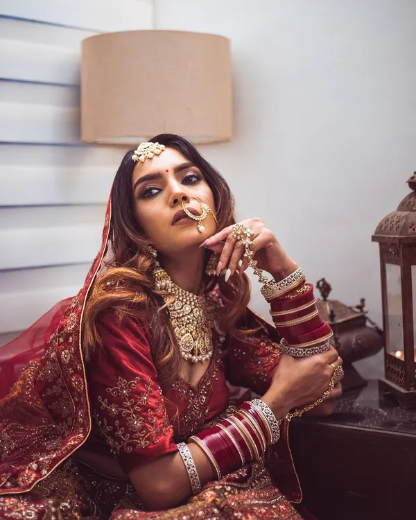 A modern bride with a traditional soul. Her direct gaze and confident pose are balanced by the classic bridal attire, including the intricate nath and maang tikka, creating a powerful and contemporary bridal portrait.
