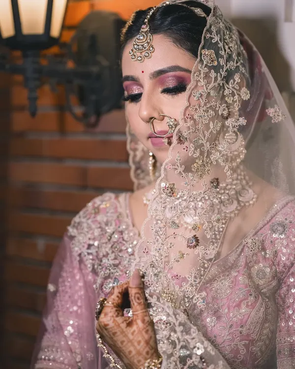 A serene moment as the bride adjusts her veil. I love capturing these quiet, reflective shots that highlight the intricate details of the bridal look, from the makeup to the embroidery.