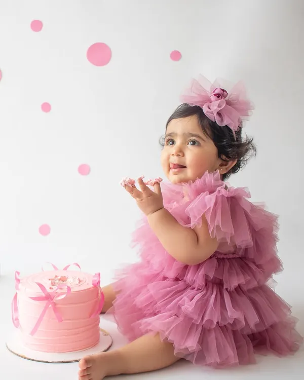 A first birthday is a huge milestone, and a cake smash is the perfect way to celebrate. This little one is having the best time with her very own pink cake in a clean, minimalist setup.