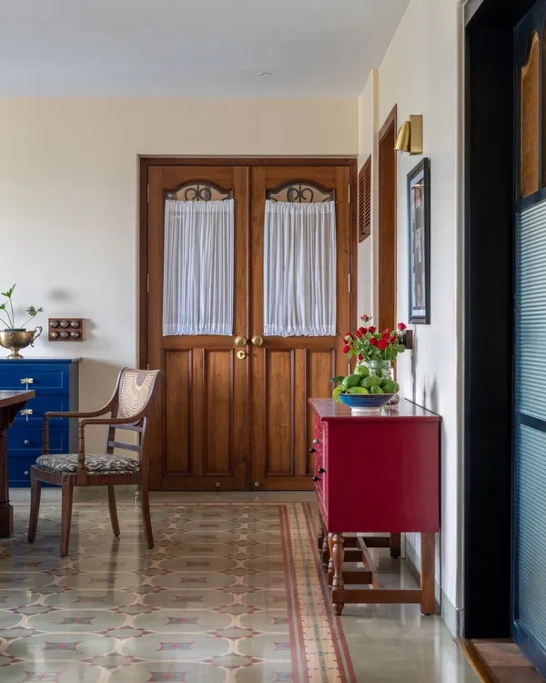 This Calcutta living room was designed to hold a family's energy and memories. We kept the soul of their old bungalow by using warm woods, patterned heritage tiles, and pops of color like this red console. The goal was to create a space that feels generous and grounded, where stories can be passed down for generations.
