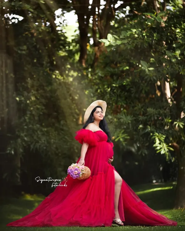 A fairytale moment in the woods. The flowing red gown and sun-dappled light create a truly magical outdoor maternity portrait.