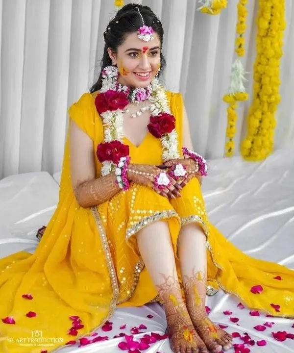 A radiant bride during her haldi ceremony, with her beautiful bridal mehendi on her hands and feet adding to her glow.