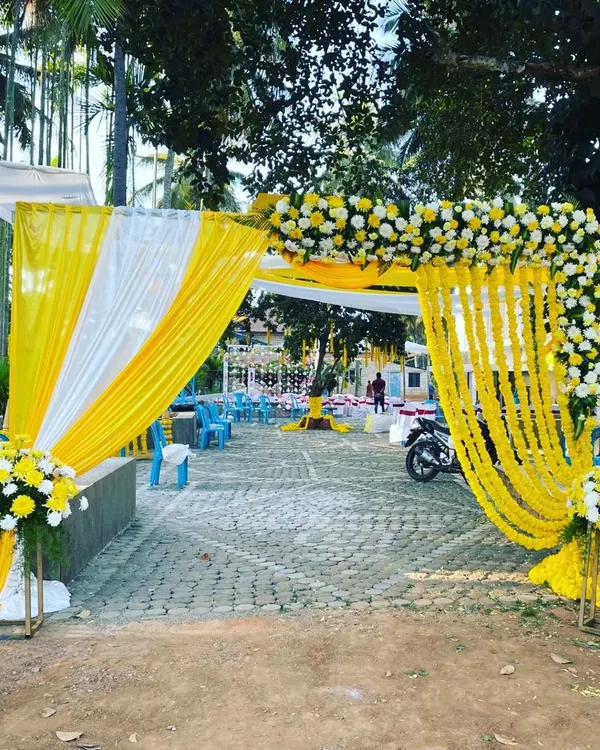 I designed this cheerful entrance for a haldi ceremony using bright yellow and white fabric drapes. The arch is adorned with marigold garlands and floral bouquets, setting a festive tone right from the start.