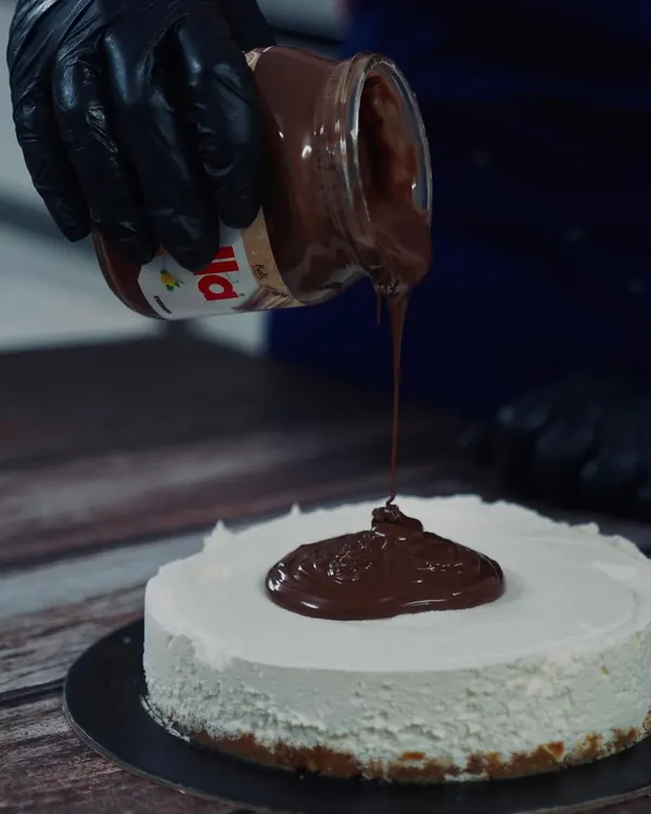That Nutella pour is everything. My eggless Nutella cheesecake is a crowd-pleaser, featuring a crunchy biscuit base, a light cream cheese filling, and a thick, decadent layer of pure Nutella.