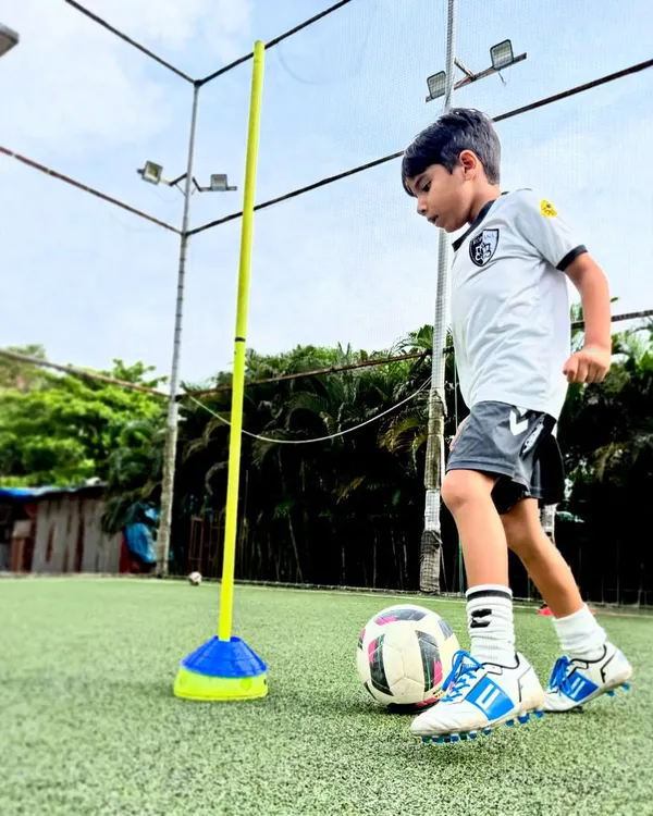 A young player focuses on close control while navigating an agility pole, a core drill for improving dribbling in tight spaces.