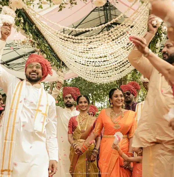 The grand exit, showered with flowers and blessings. This wide shot captures the immense joy of the couple and their families at the conclusion of the ceremony.