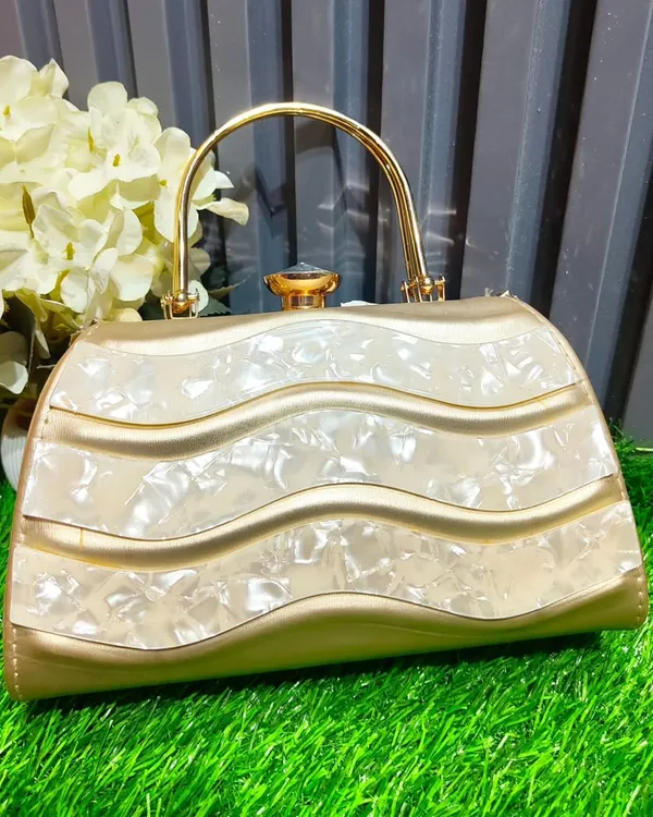 This elegant gold and mother-of-pearl clutch with a wavy design is a unique piece that will elevate any outfit. It's perfect for holding your essentials at a wedding.