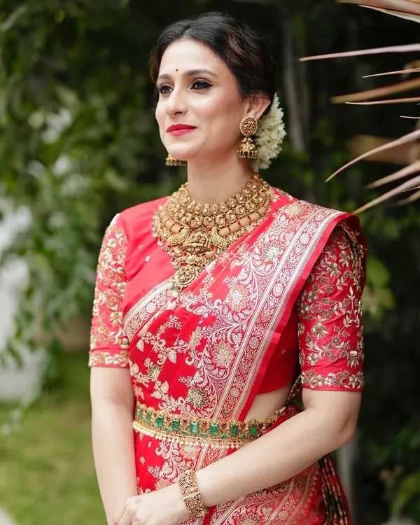 This is the embodiment of bridal opulence. A pure Katan silk handwoven Banarasi saree in a radiant red, paired with a meticulously hand-embroidered blouse. The intricate gold zari work and the rich texture of the silk make this an heirloom piece, perfect for a bride on her wedding day.