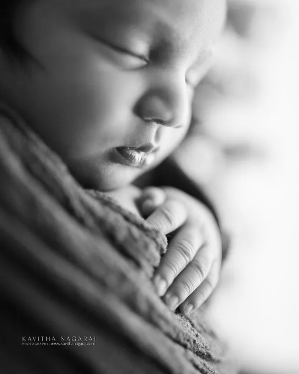 A macro shot in black and white, focusing on the delicate fingers and lips of a newborn. This style magnifies the tiniest wonders and turns them into art.