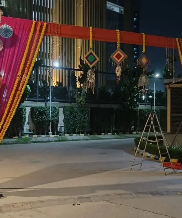This is a festive gate I designed for a Mehendi or Sangeet night. It features a bright pink and orange fabric frame, decorated with marigold flower strings, paper pinwheels, and hanging Rajasthani umbrellas.