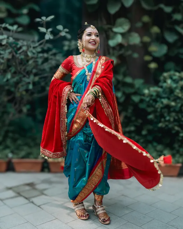 A full-length portrait of a stunning Marathi bride, showing off the beautiful drape of her traditional Nauwari saree and red velvet shawl.