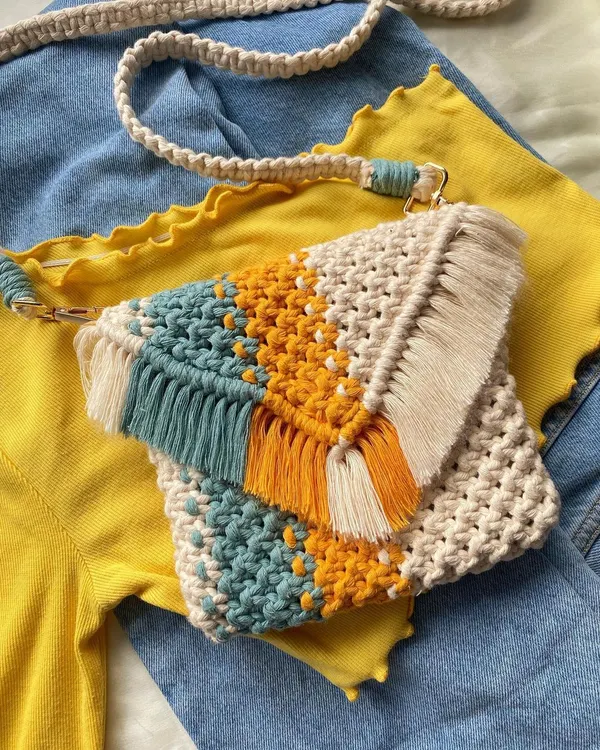 I'm in love with this color combination! 💛 This yellow, teal, and cream macrame sling bag has such a fresh and happy vibe. It's styled as a crossbody bag here, showing off the detachable strap and fringe detail on the flap. It’s the perfect accessory for a sunny day out.