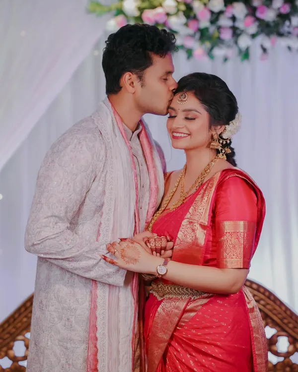 A tender moment from an engagement ceremony, where the groom kisses the bride's forehead. This candid shot captures the love and emotion of the occasion.