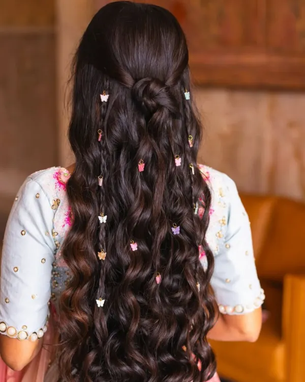 This beautiful, long, and wavy hairstyle was created using clip-in extensions. The added butterfly clips make it a perfect look for a festive or special occasion.