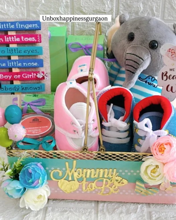This gender-neutral baby shower hamper is a perfect gift for expecting parents. It's packed with adorable items like a plush elephant, tiny pink and blue booties, and a charming "We Can Bearly Wait" sign, all beautifully arranged in a custom "Mommy to Be" basket.