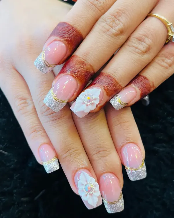 The perfect bridal nails, featuring a classic French manicure with silver glitter, gold accents, and stunning 3D flowers.